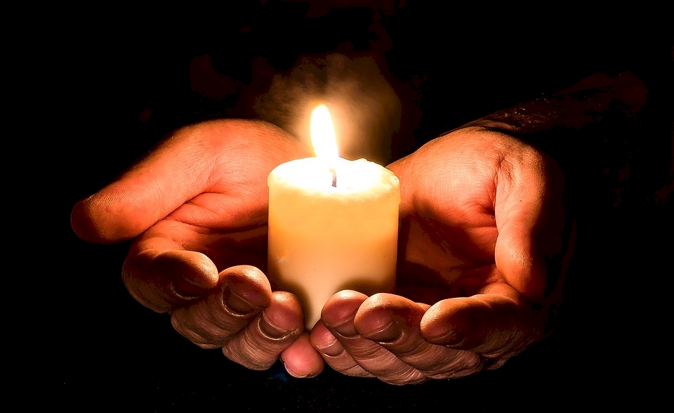 Candle cradled in cupped hands